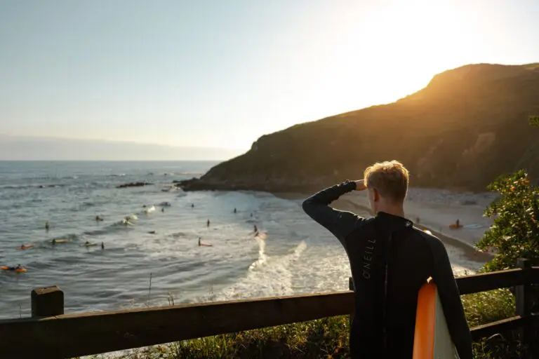 surfer looking out at the ocean at sunset